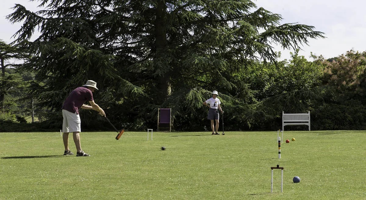 croquet match on grassy field with two players in background
