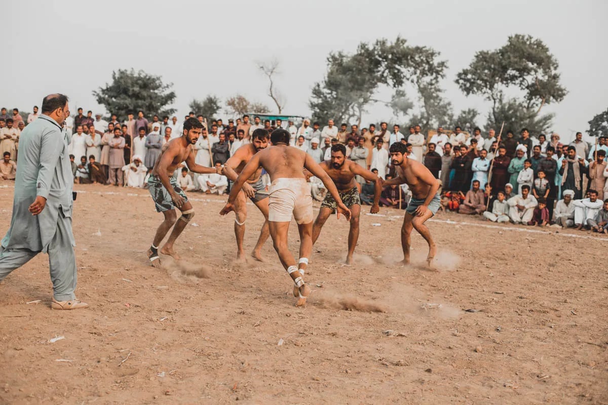 men on dirt field in semi circle playing kabaddi
