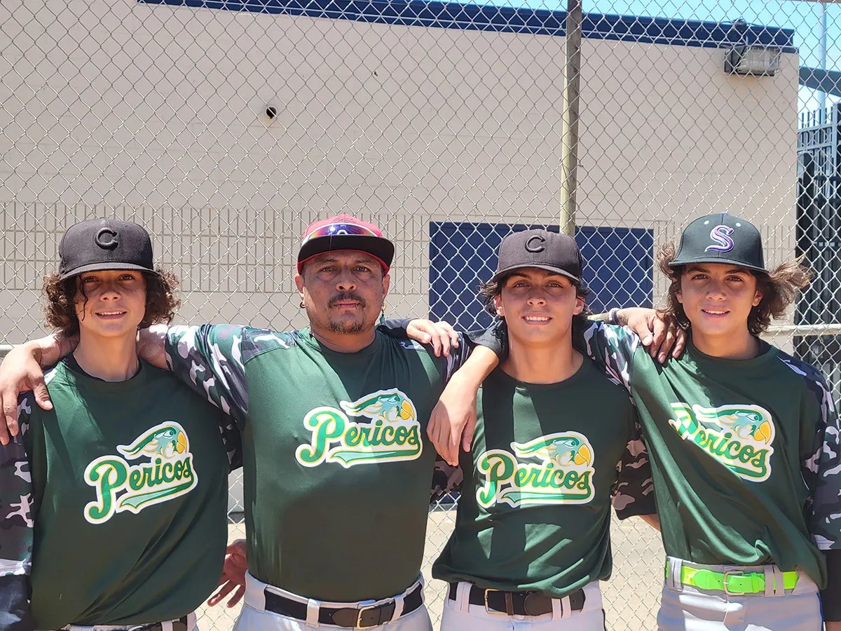 David Carrillo and three of his five sons in green baseball uniforms with arms linked around each other