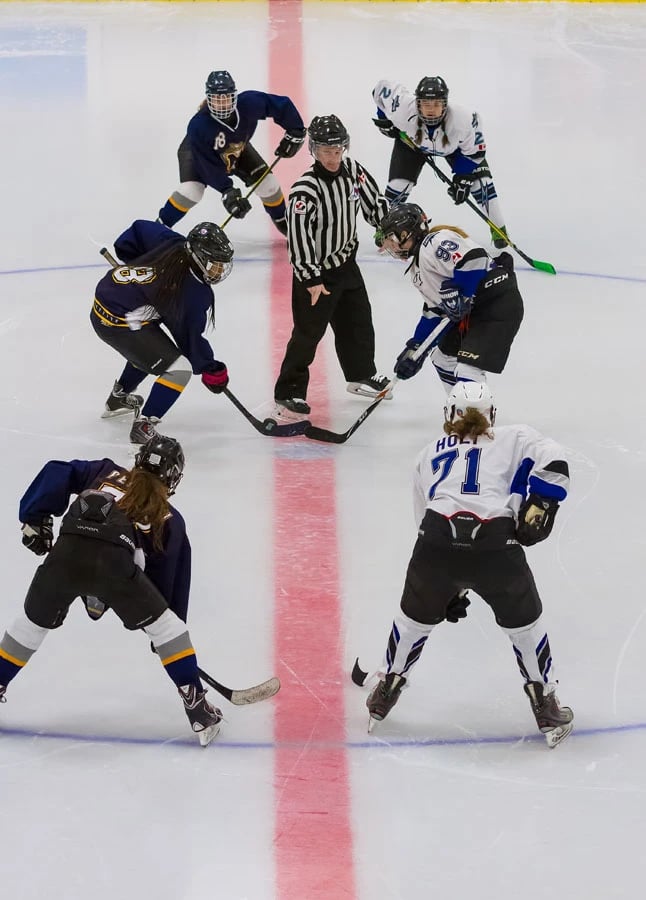 Female hockey players from different teams facing off on the ice
