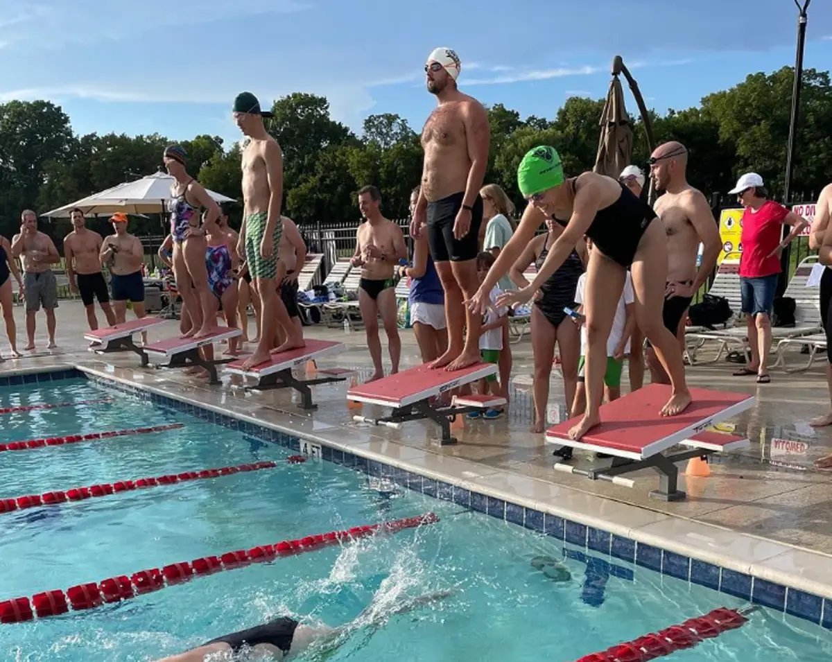 Swimmers in 20s and 30s on platforms getting ready to jump in pool