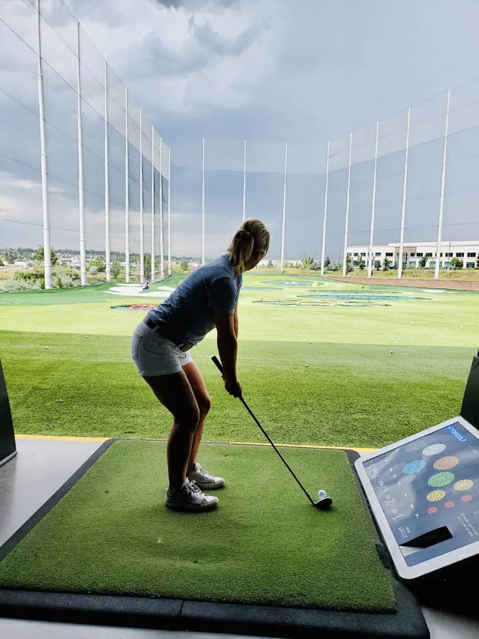 woman at Top Golf getting ready to tee off showing low intensity calorie burn sport

