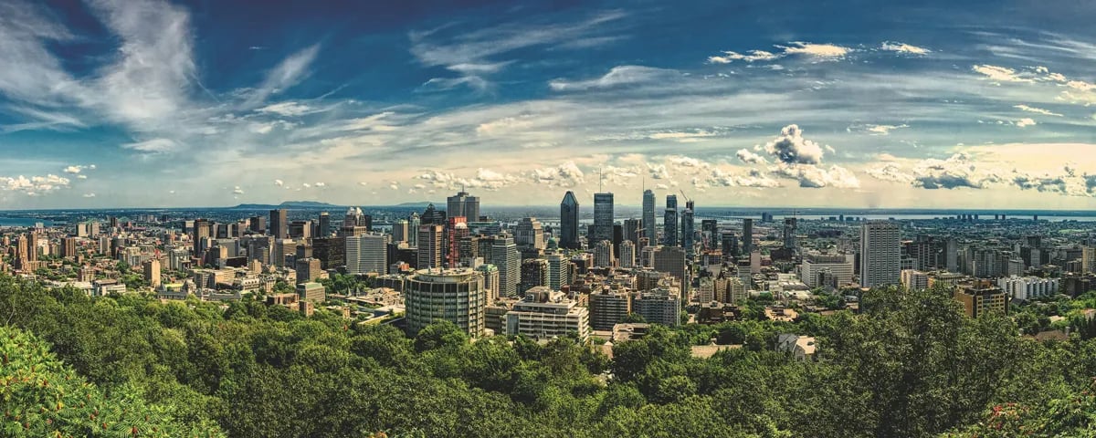 Montreal skyline with downtown skyscrapers in distance and white clouds across blue sky