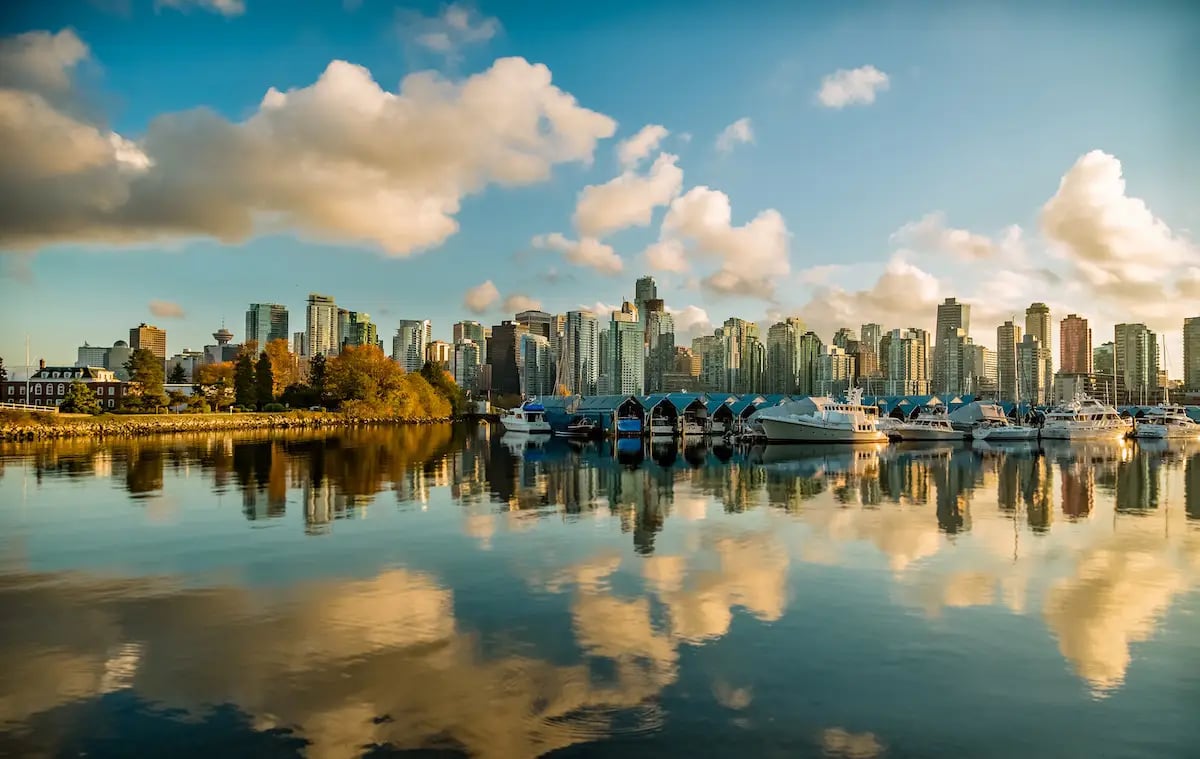 Vancouver BC skyline with cityscape in background and water in foreground with clouds reflecting off the water