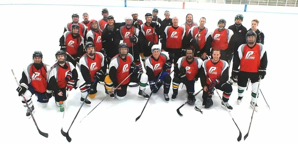 Adult sports camp group photo of ice hockey players on ice in uniform with sticks out front