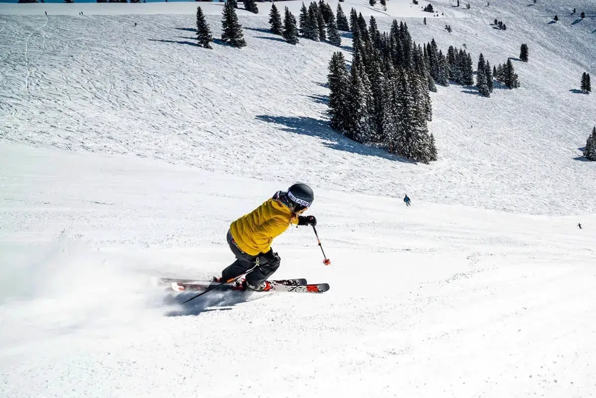 skier in yellow parka skiing downhill
