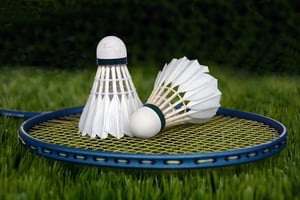 close up of badminton shuttlecocks on top of a racquet in grass