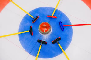 overhead view of six curling brooms and stone in center