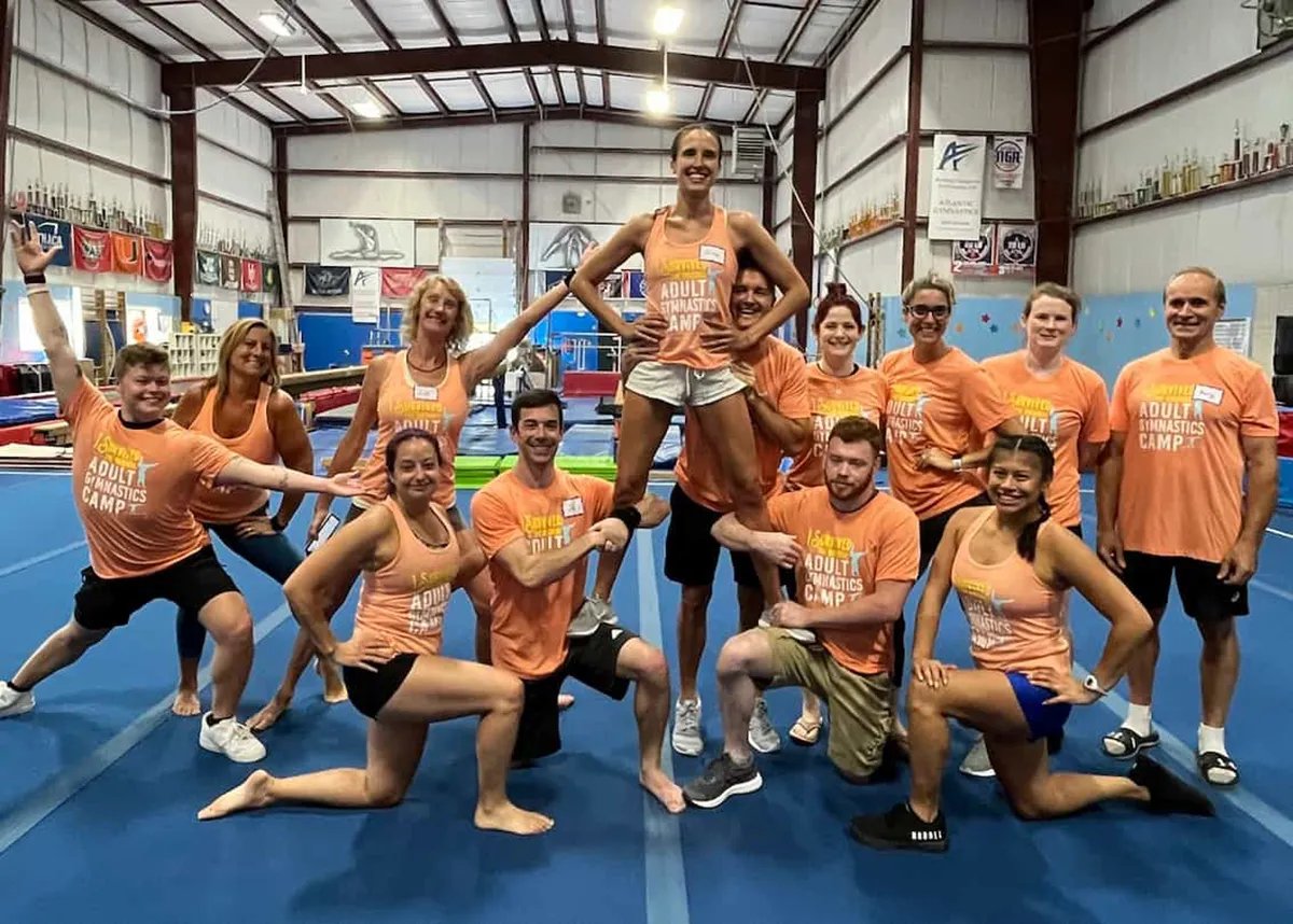adult gymnastics camp group photo with men and women posting on gym mat