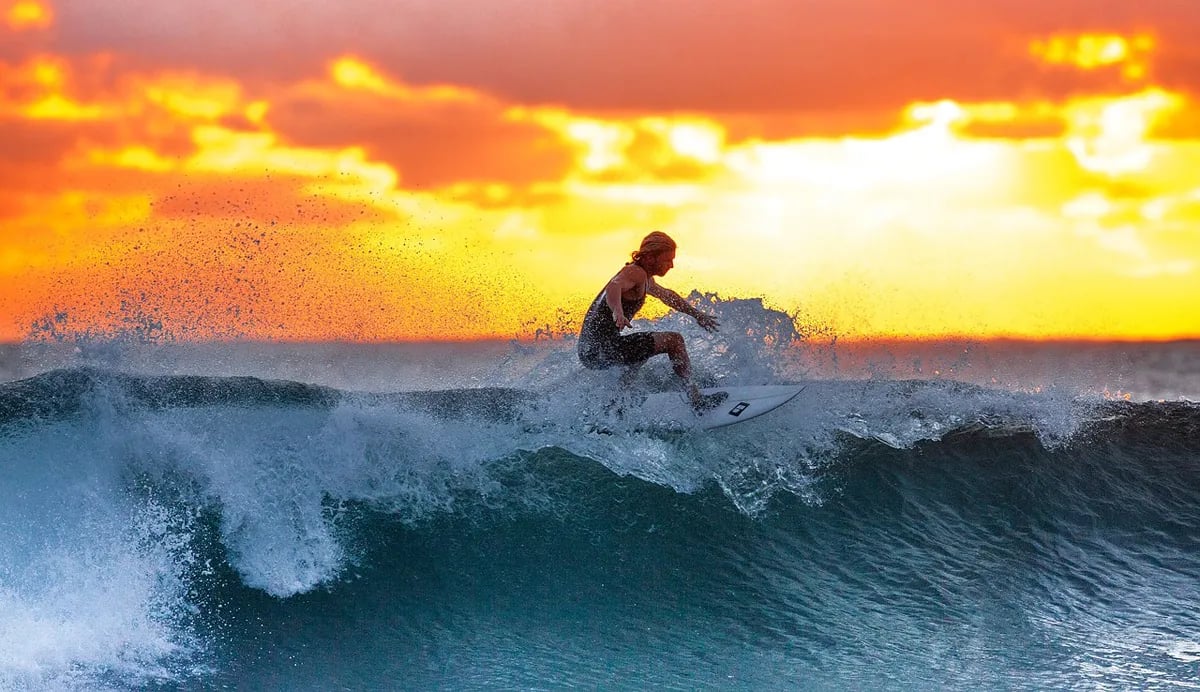 guy surfing wave at sunset