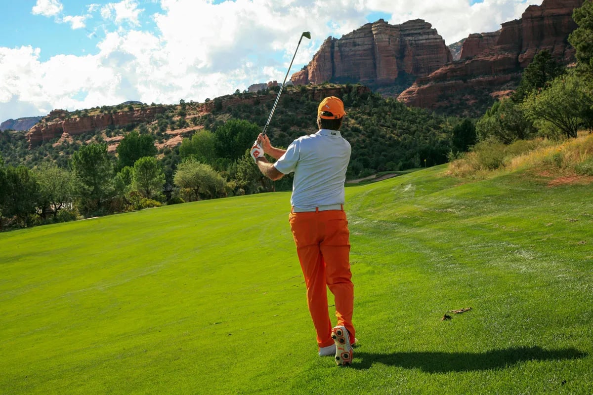 folger in red pants teeing off toward mountains