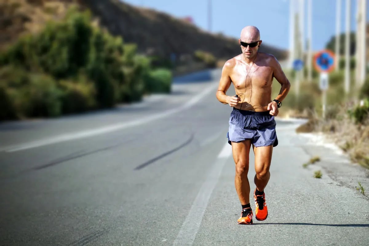 lone bald runner without shirt on road