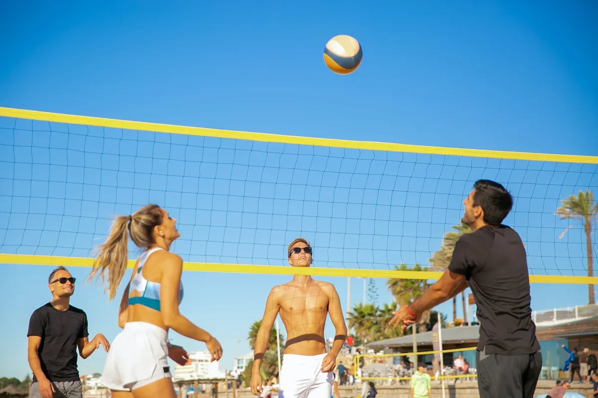 three guys and girl playing beach volleyball