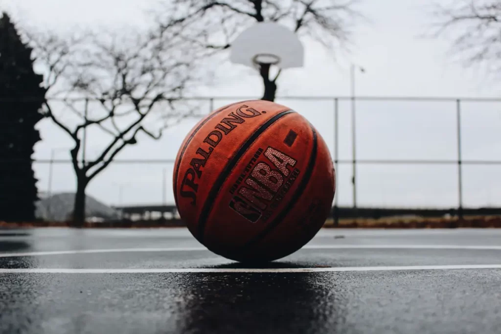 closeup of Spalding basketball on a basketball court with a blurry view of basketball hoop in background
