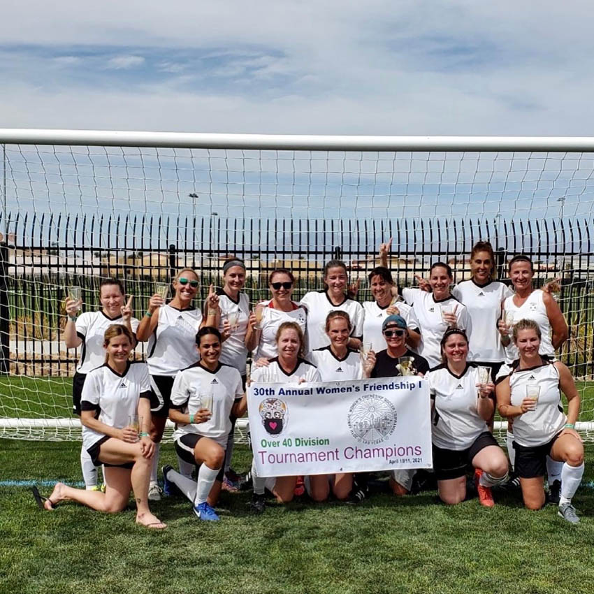 soccer women posing with champion banner in front of goal