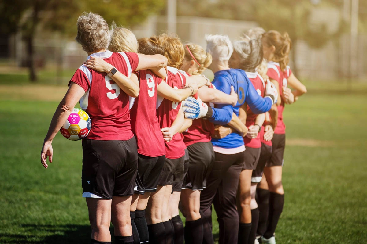 soccer women lined up in a row with arms across each other's shoulders