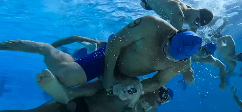 Underwater Torpedo League match guys trying to steal torpedo out of another guy's hands underwater.