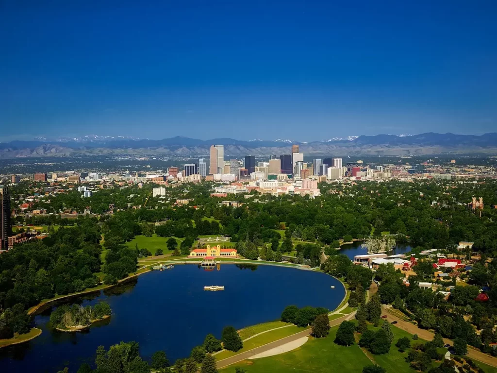 Aerial veiw of downtown denver with a lake in front and mountains in skyline.