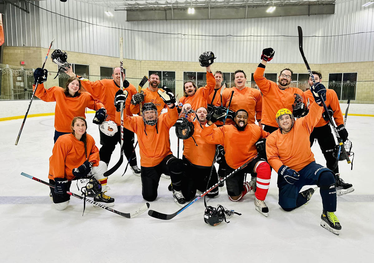 John Moores' team hockey photo on the ice with players pumping fists in the air